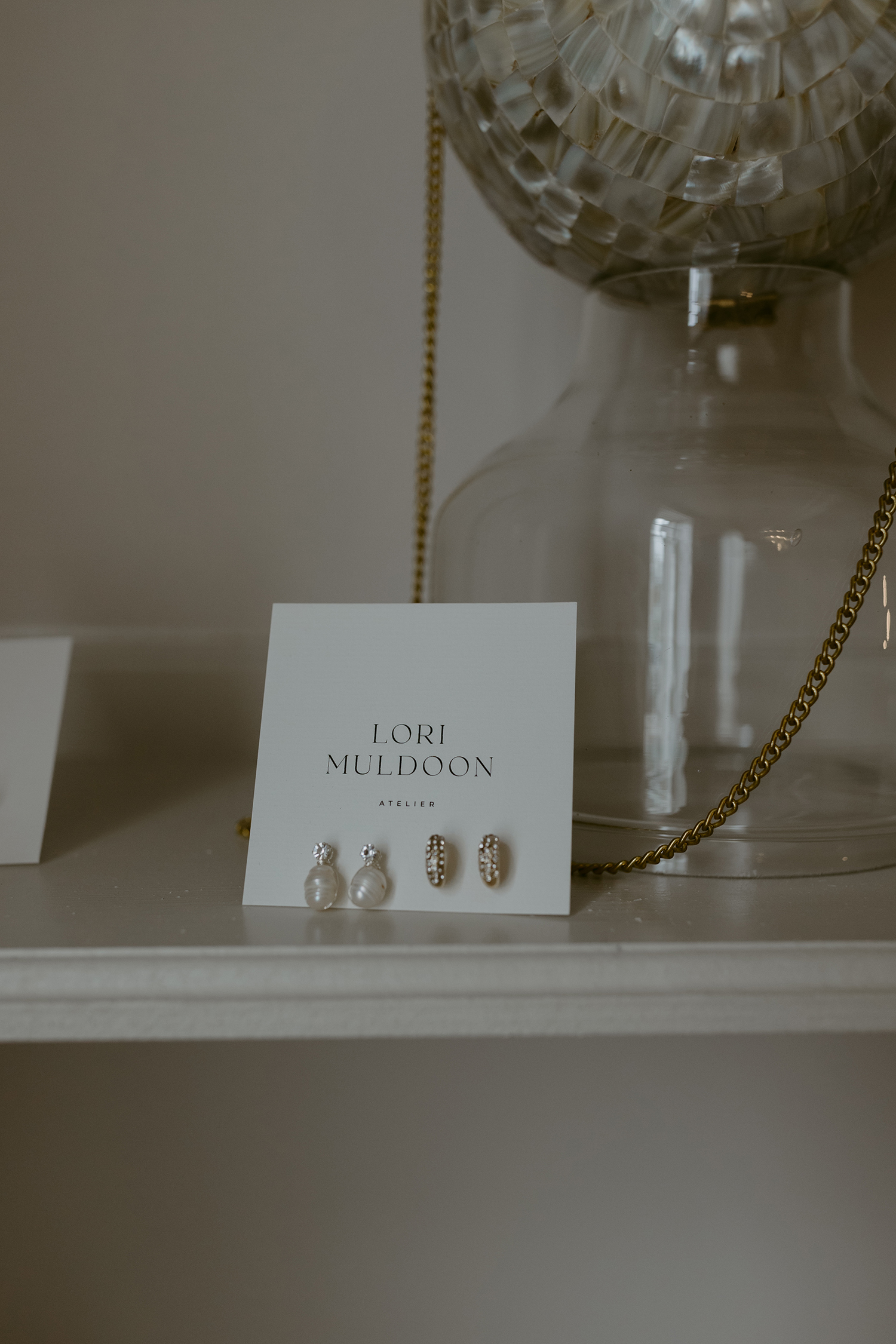 Lori Muldoon designer earrings displayed on studio shelf with Georgian interior background